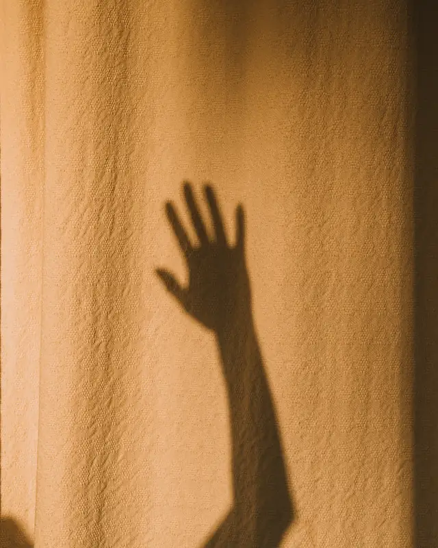 Sombra de una mano sobre un muro de arena