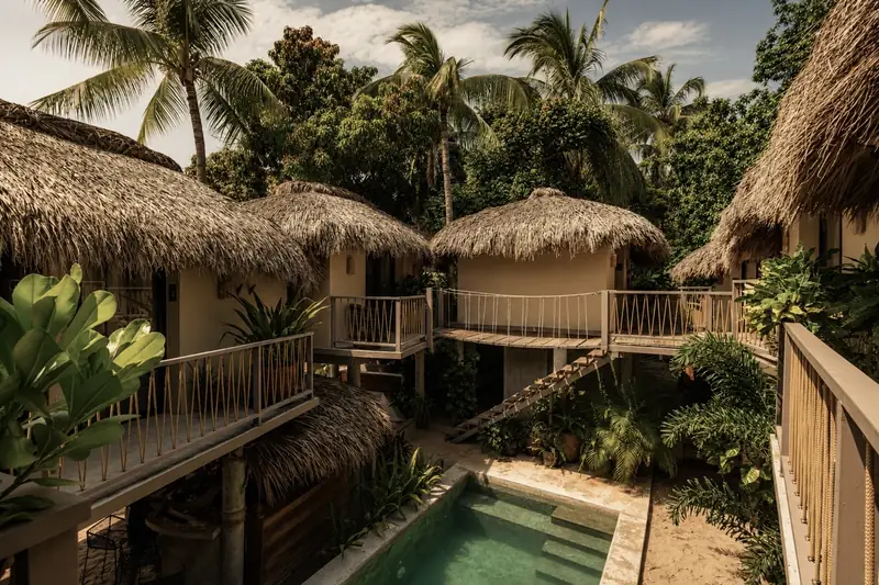 Bungalows con techo de palapa junto a la alberca de raíz